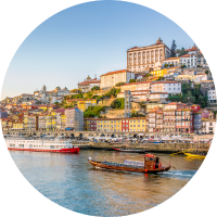 View of boats on the Duoro River and the city of Porto at sunset, where you can have travel insurance for Portugal