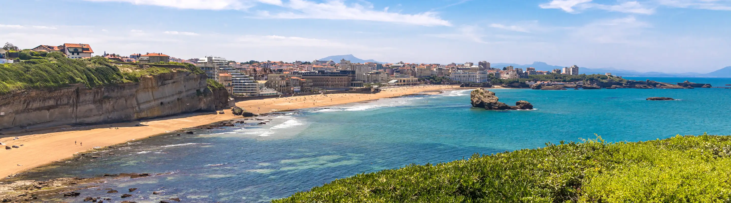 View of the water, shore, and distant buildings at Bay of Biarritz, highlighting travel insurance for France trips