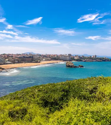 View of the water, shore, and distant buildings at Bay of Biarritz, highlighting travel insurance for France trips