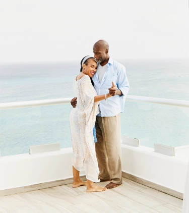 Senior couple with travel insurance for their all-inclusive vacation dancing on a hotel balcony