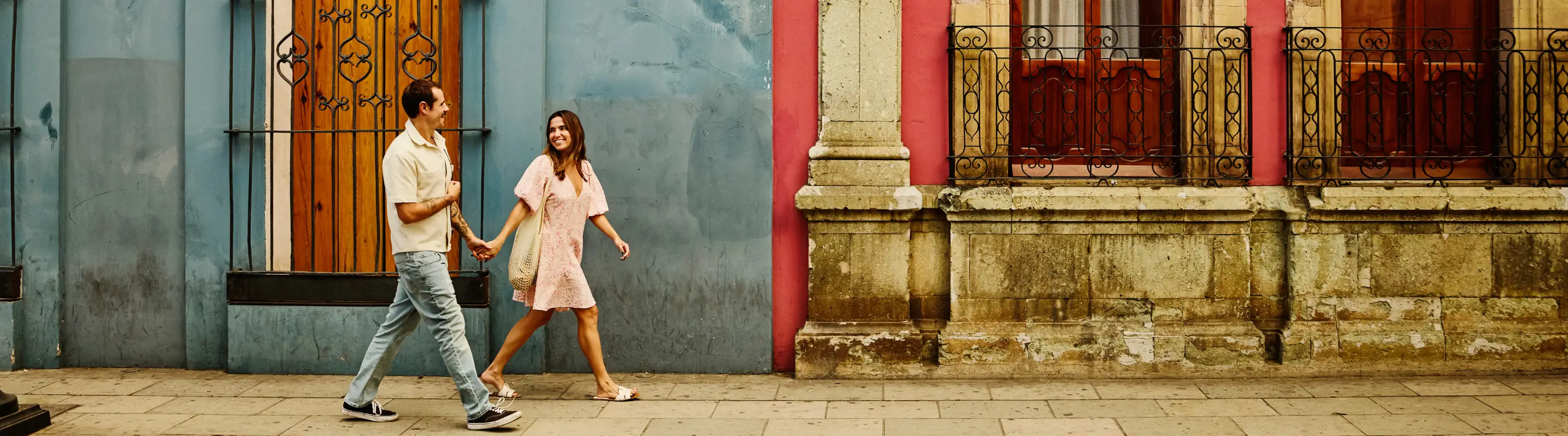 Young couple with travel insurance for Mexico walking on the street and holding hands