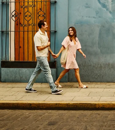 Young couple with travel insurance for Mexico walking on the street and holding hands