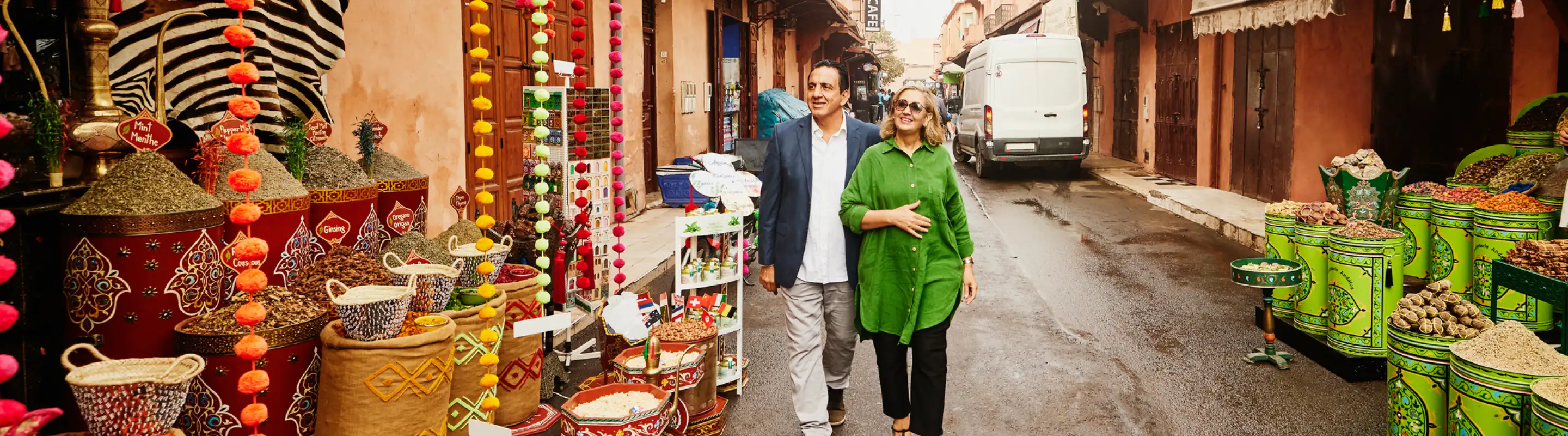 Middle-aged couple with flight insurance walking past spices in a market in Marrakech