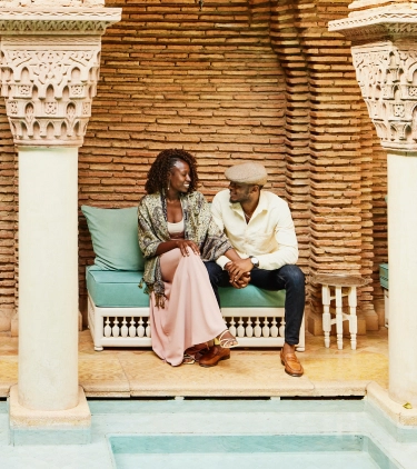 a young, Black couple with long-term travel insurance sits in a Moroccan riad-style courtyard 