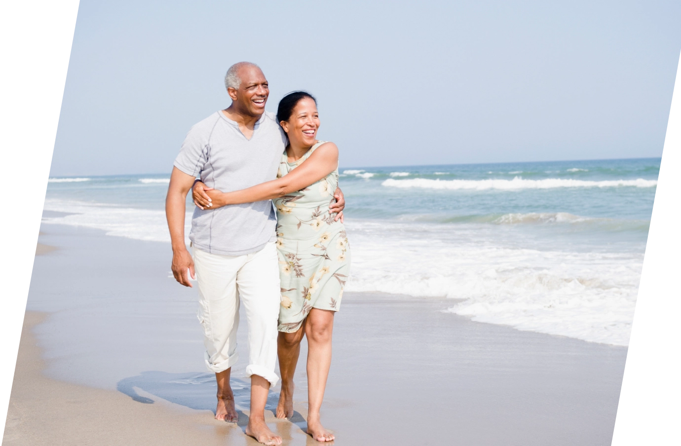 Middle-aged couple with travel insurance for New York embracing while walking on the beach in Long Island