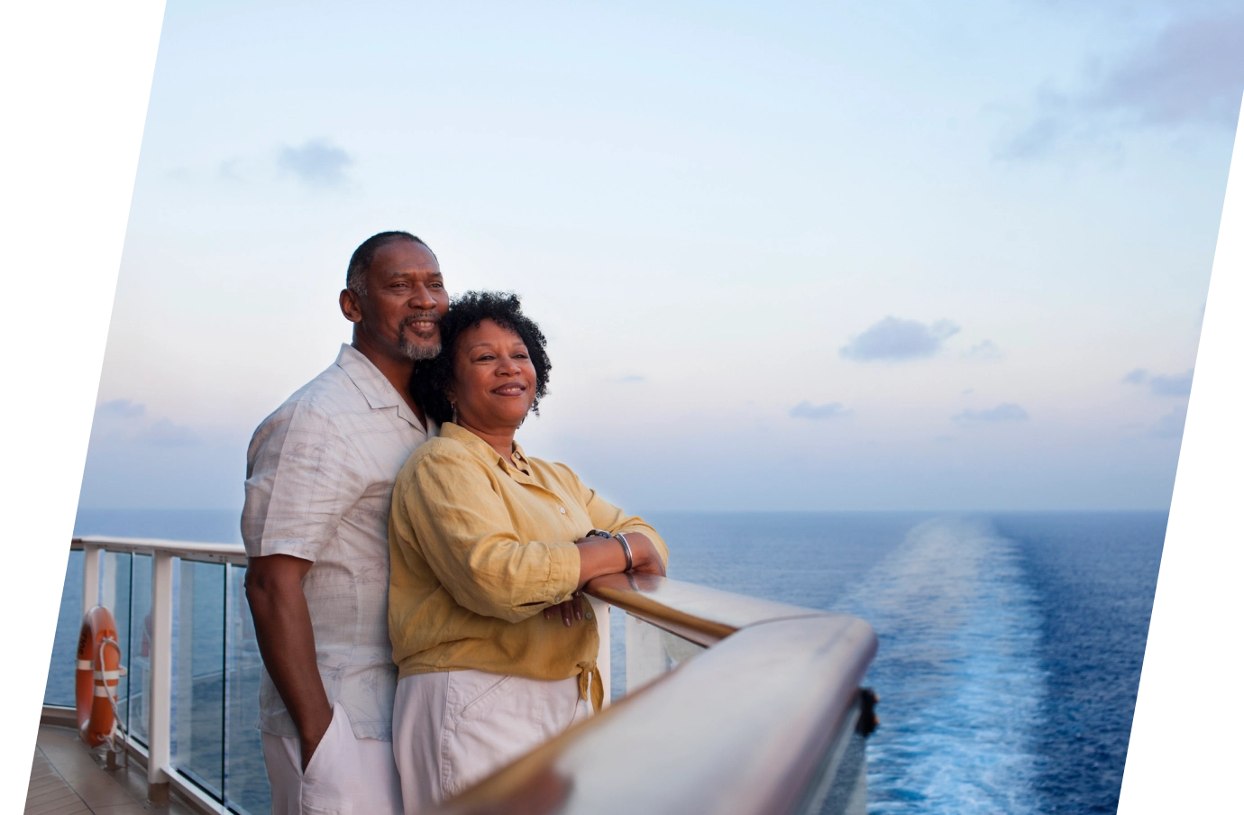 Middle-aged couple with last-minute travel insurance on a cruise ship deck looking out at the ocean