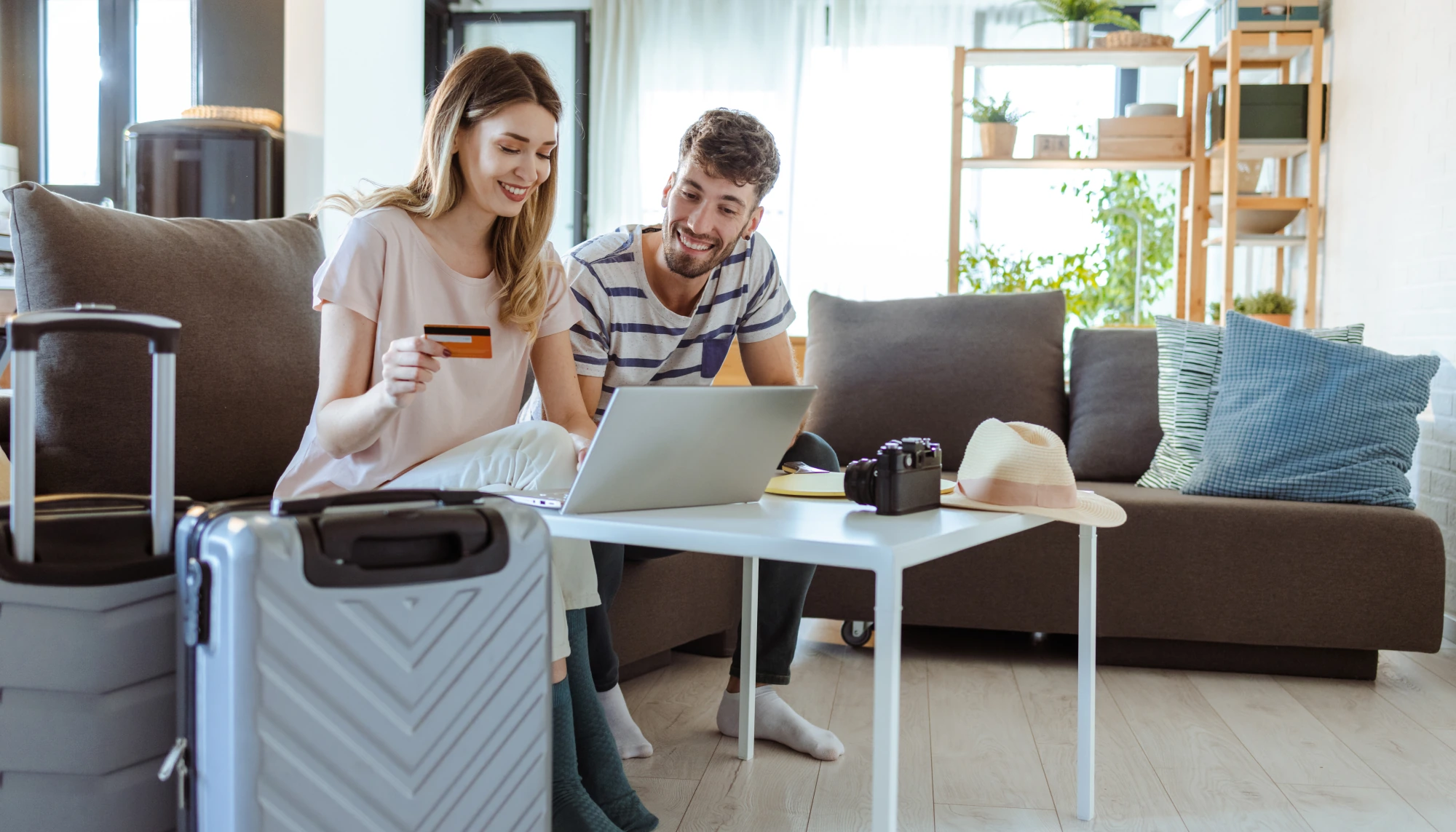 Man and woman holding a credit card while looking at a laptop at credit card travel insurance