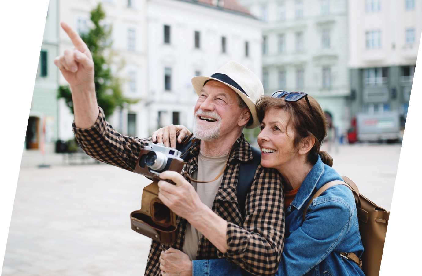 an elderly couple with travel insurance for city trips holds a camera and sightsees in a city setting 