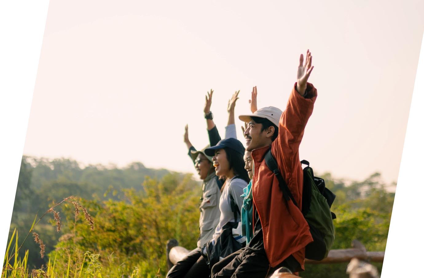 a family of four raises their hands into the air as they take in scenic views on vacation, protected by backpacker travel insurance 