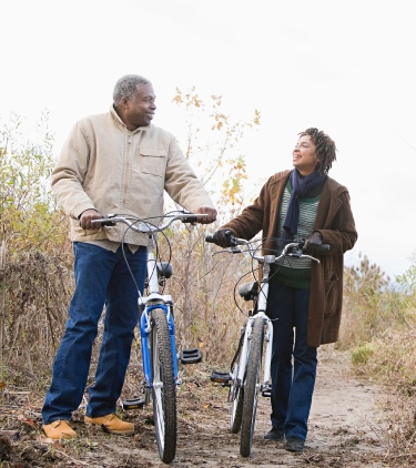 a father and daughter with travel insurance for New York walking their bikes on a nature trail upstate 
