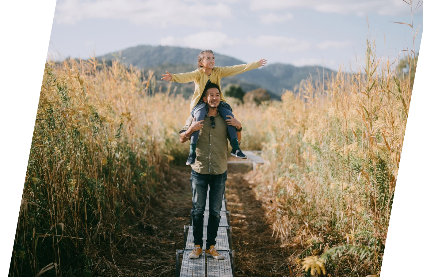 a young daughter on her father's shoulders, posing for a picture in nature and knowing their protected with accidental death travel insurance
