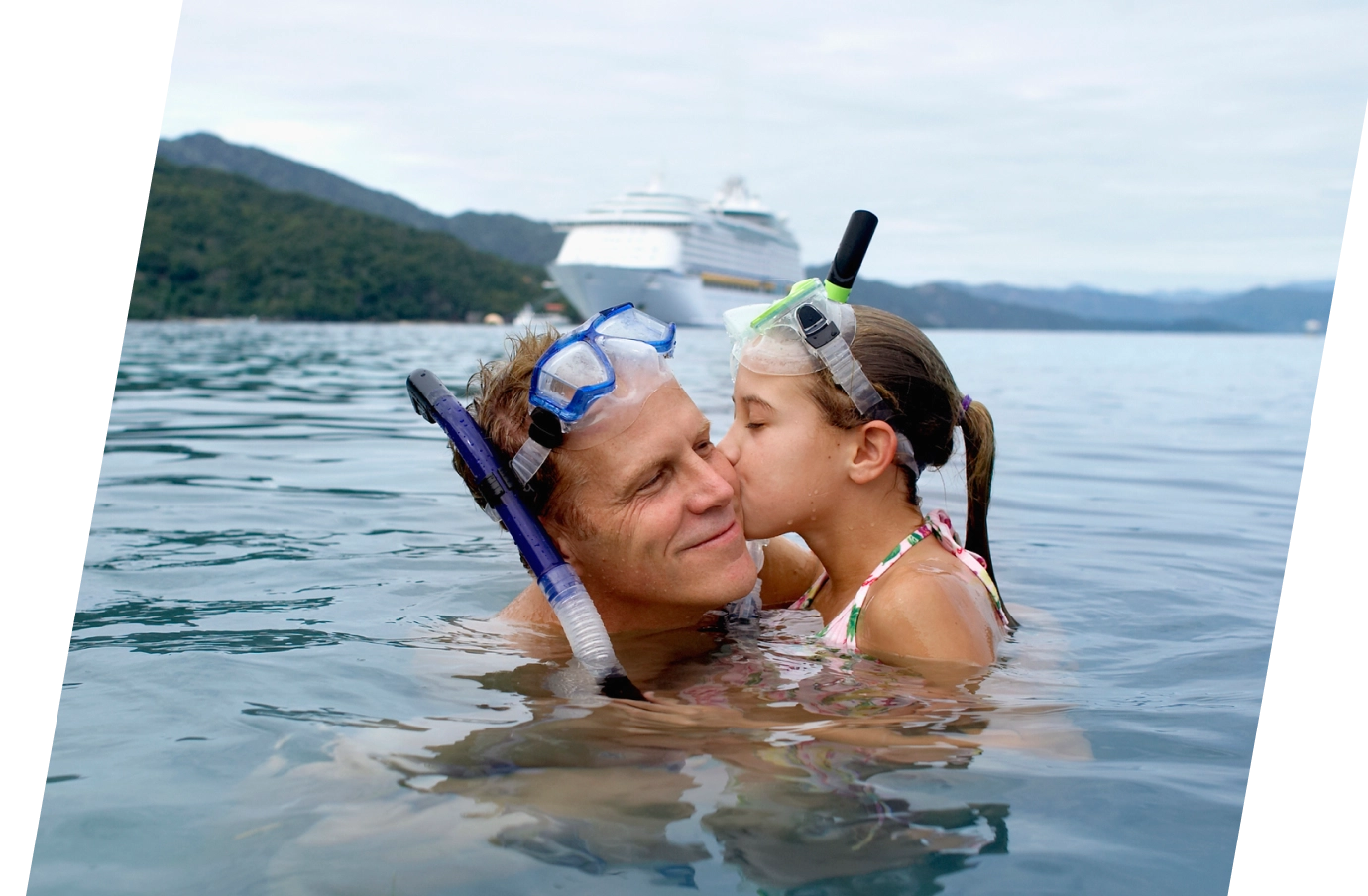 a father-daughter duo with cruise travel insurance wear snorkel gear in the water on an excursion nearby their ship