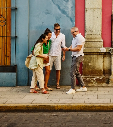 a group of friends with travel insurance for COVID-19, looking at their maps on vacation nearby historic buildings