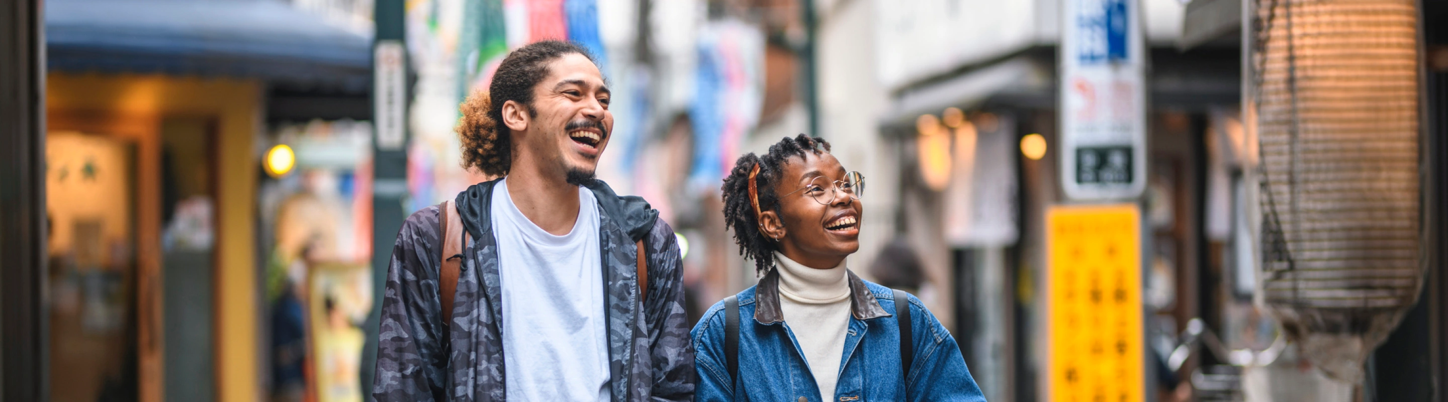 two friends with travel insurance for Japan, laughing as they walk through Tokyo 
