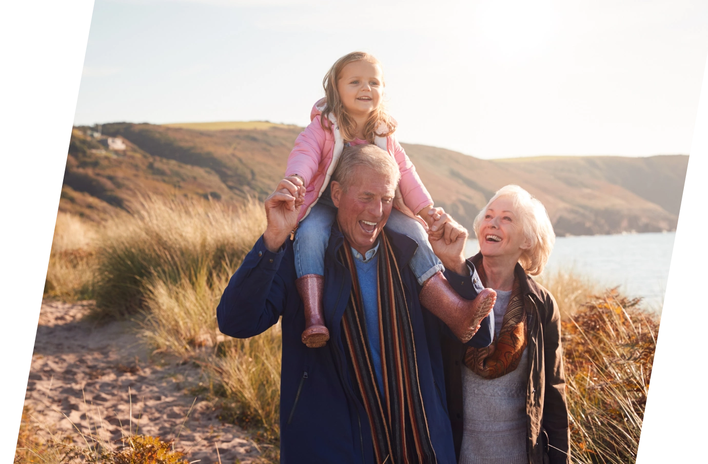 grandparents with travel insurance for COVID-19, holding their granddaughter as they enjoy a walk on the sand by the ocean 