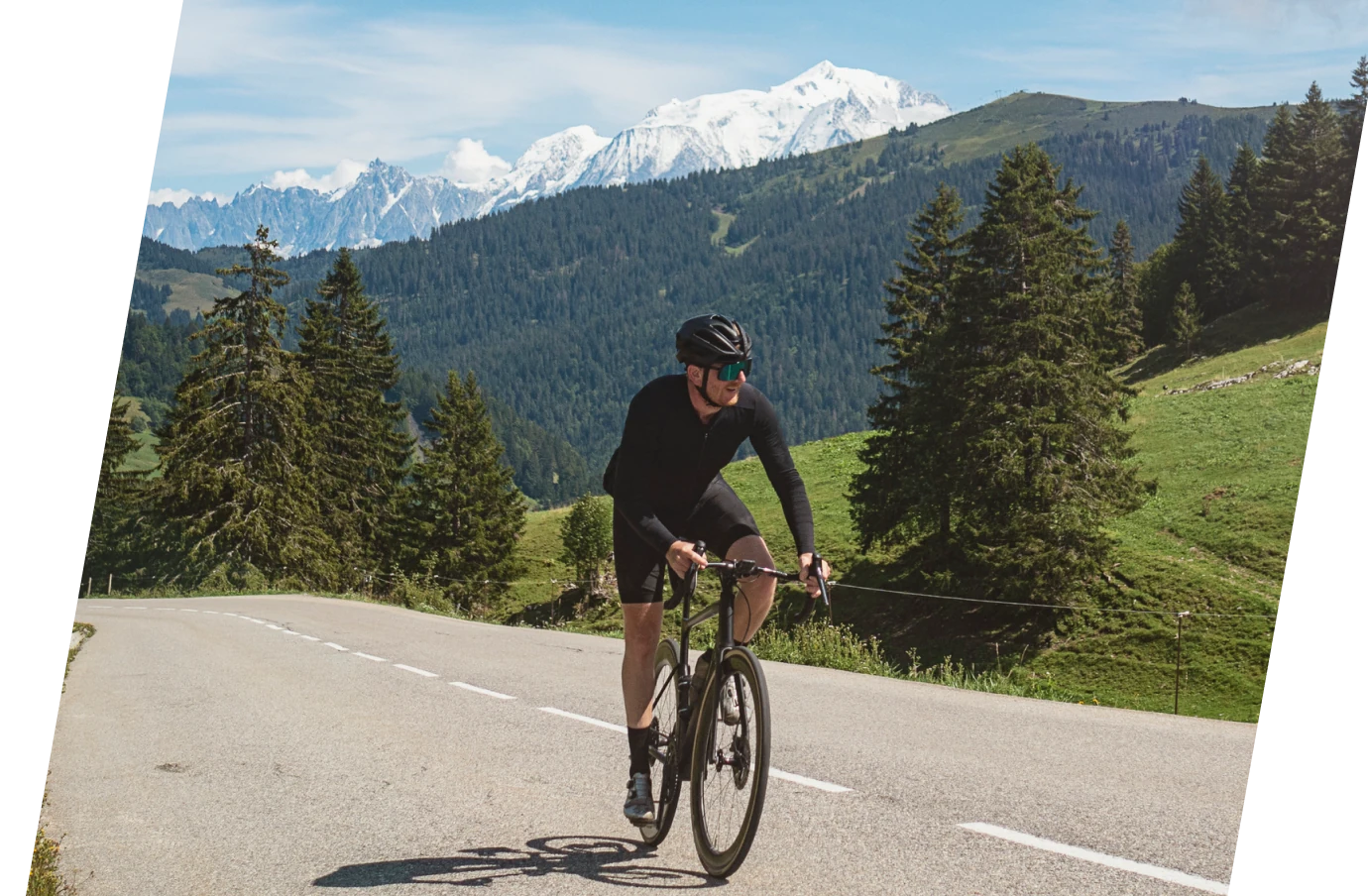 man with travel insurance for France, biking on a road with a backdrop of forests and mountains 