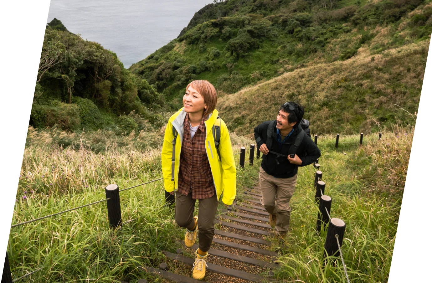 a man and woman with travel insurance for Japan on a hike near the water 