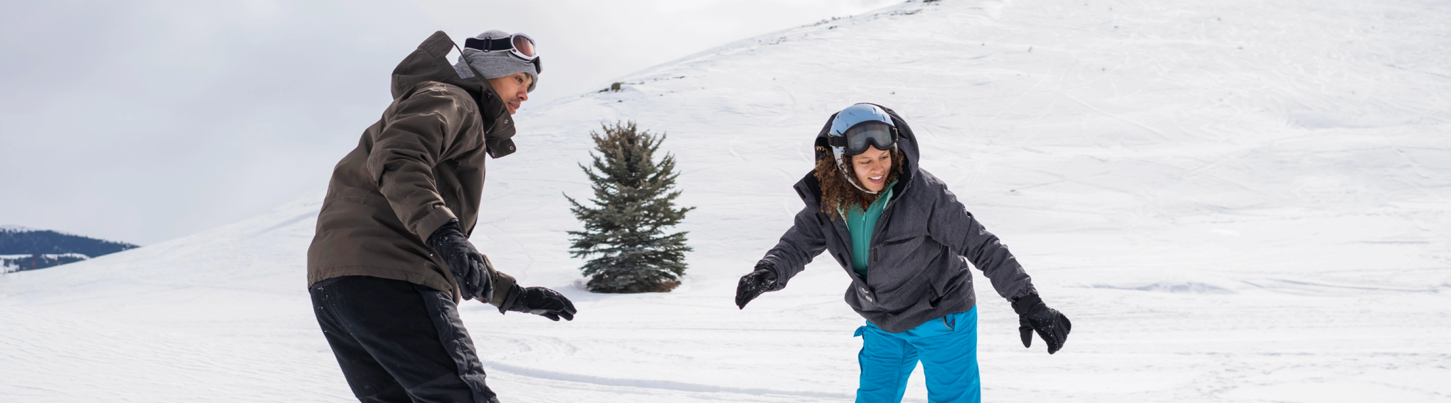 a young man and woman snowboard down a snowy slope on a winter vacation after researching snowboard and ski insurance