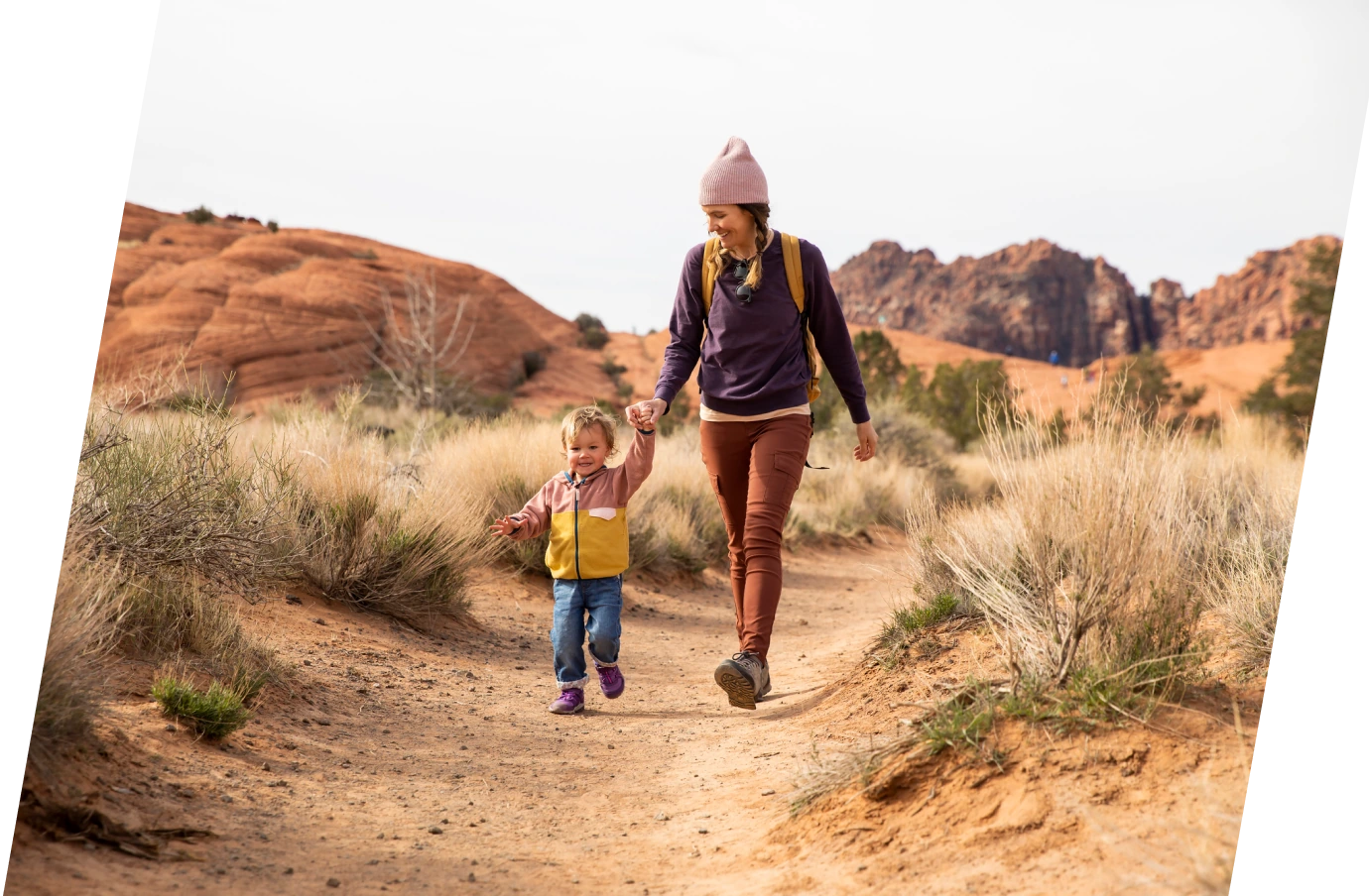 Mother with travel insurance plans holding hands with toddler son and walking in the desert