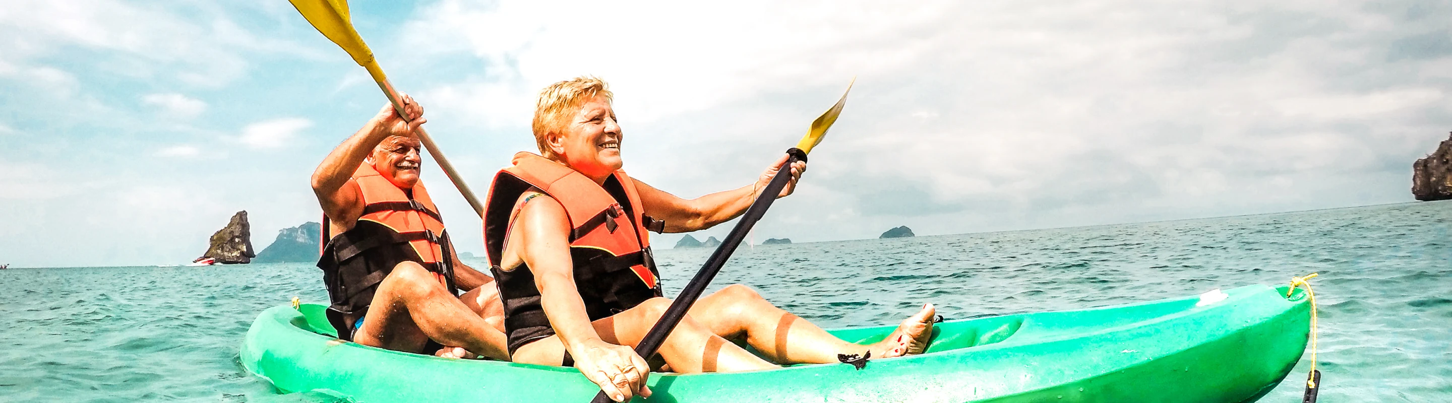 Senior couple with travel insurance for Thailand wearing life jackets while kayaking