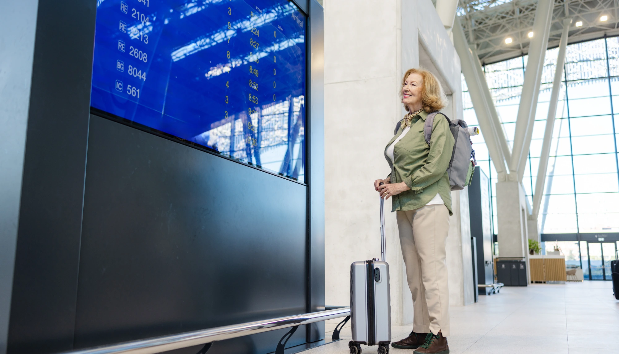 a woman looks up her flight information at the airport, wondering, "does travel insurance cover flight disruptions?"