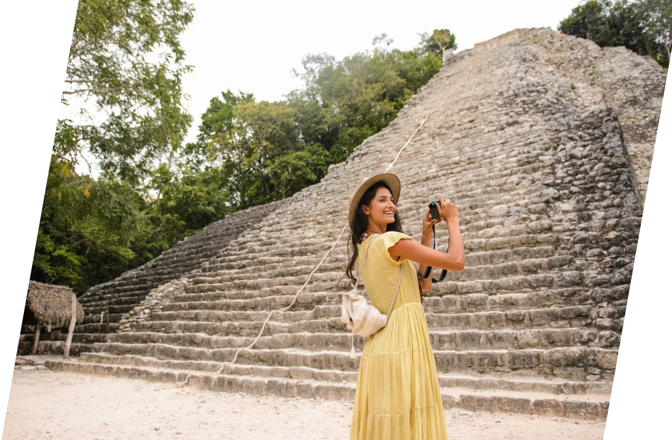 Young woman smiling and taking a picture of Mexican ruins while on vacation with travel insurance for Mexico