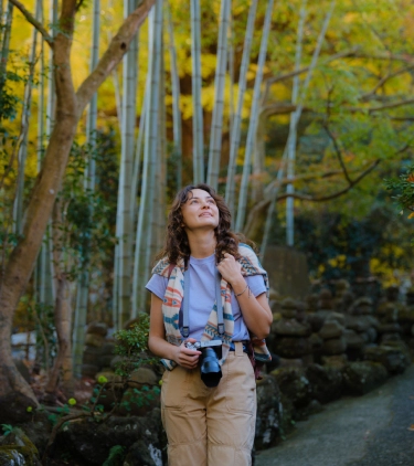 woman with travel insurance for Japan, walking through an oriental garden with bamboo