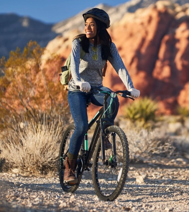 Woman, with travel insurance for Nevada, riding a bike through the desert 