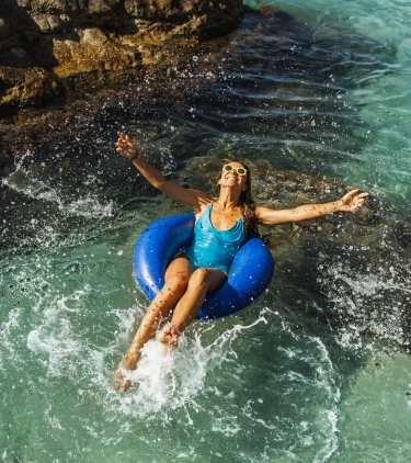 Woman with travel insurance for her all-inclusive vacation floating on an inner tube in the ocean