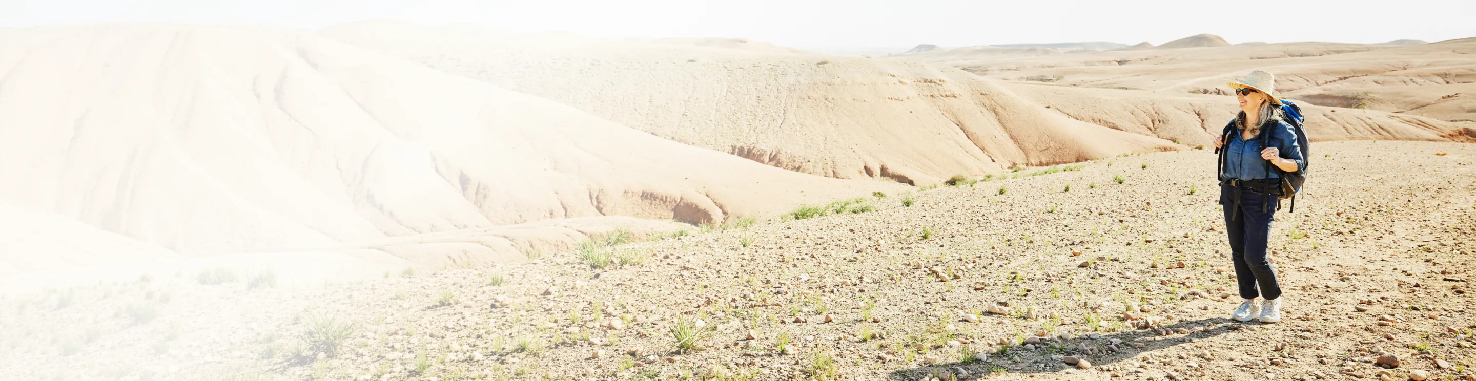 Senior woman in the Travelex affiliate program hiking in the desert with a backpack on