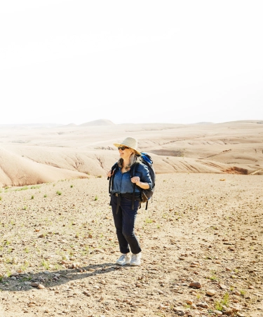 Senior woman in the Travelex affiliate program hiking in the desert with a backpack on