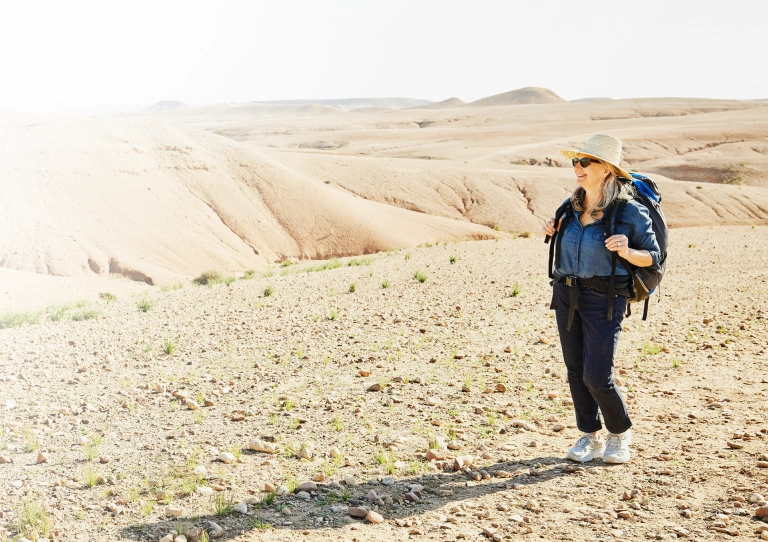 Senior woman in the Travelex affiliate program hiking in the desert with a backpack on