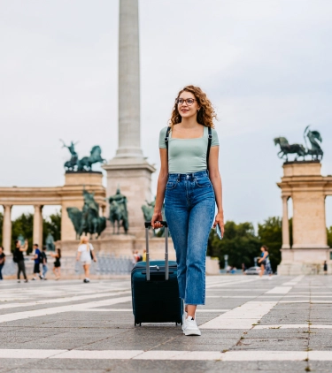 woman with baggage insurance, dragging her suitcase in Heroes' Square, Budapest 