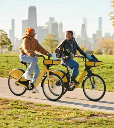 Two women riding yellow bikes through Maggie Daley Park, Chicago, with travel insurance for Illinois 