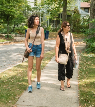two women walk through a suburban neighborhood on vacation, insured with travel insurance for Illinois 