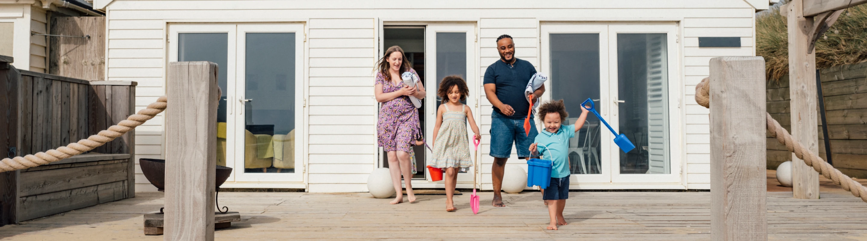 Parents with vacation rental travel insurance heading to the beach with their two young children from the back patio