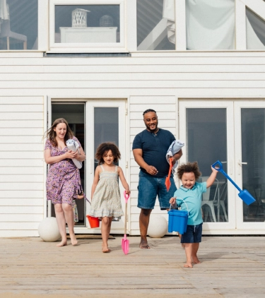 Parents with vacation rental travel insurance heading to the beach with their two young children from the back patio