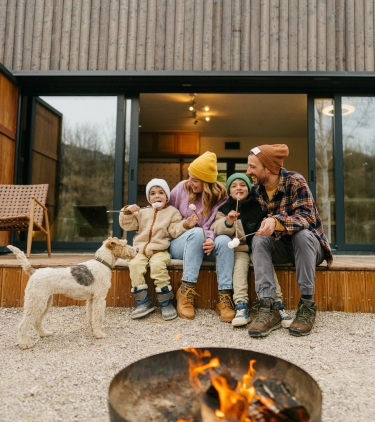 Parents with vacation rental travel insurance making smores at a cabin with their two young children
