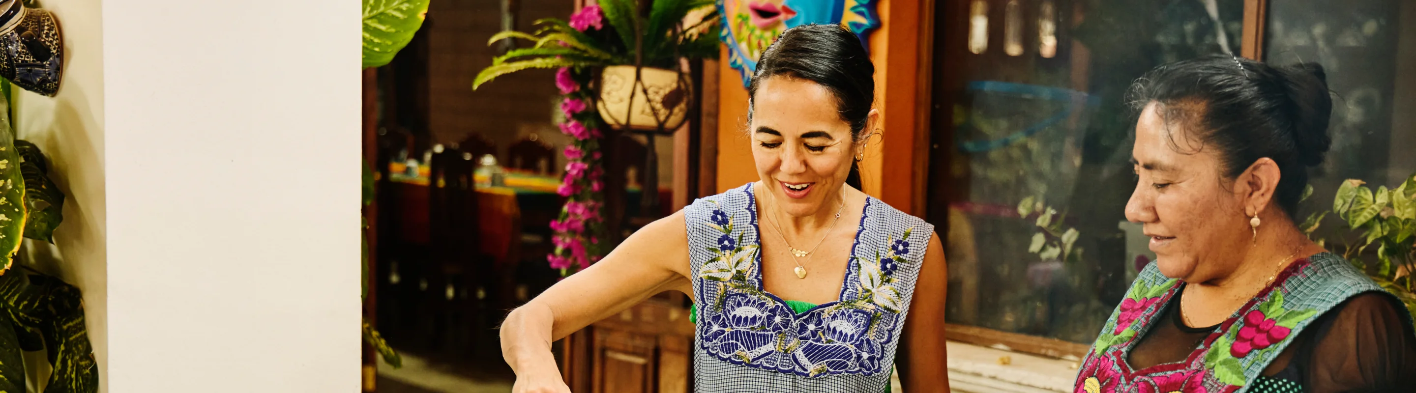 two middle-aged women with travel insurance for culinary vacations cook together in traditional embroidered clothing 