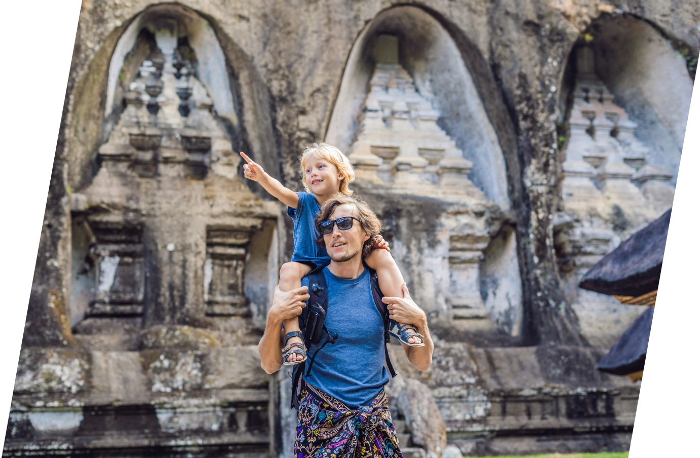 a father with pilgrimage travel insurance holds his son on his shoulders as he walks through an ancient historic site 