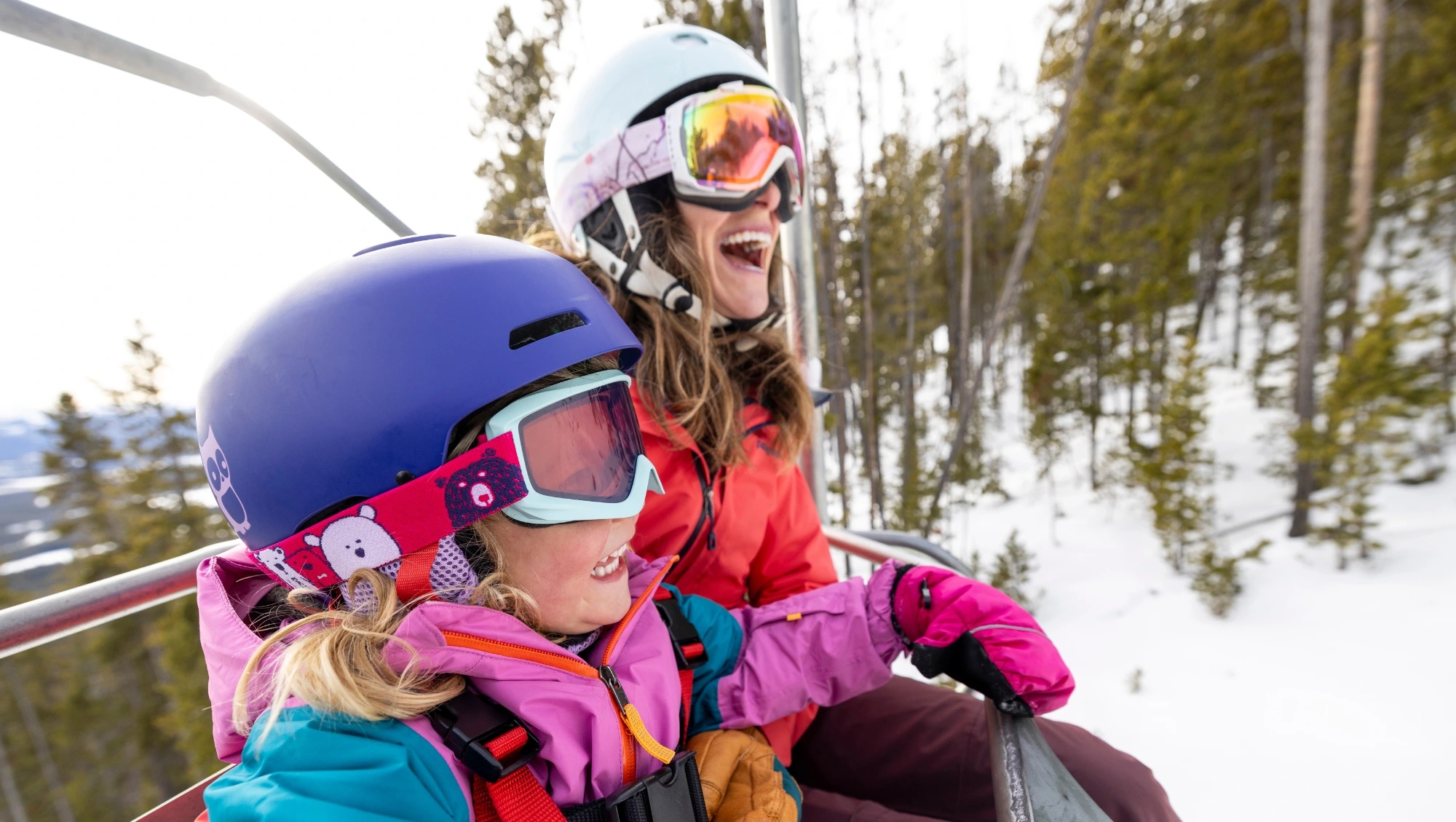 a mother and daughter in ski gear ride a chairlift up a mountain after reading about Switzerland in a Europe travel guide