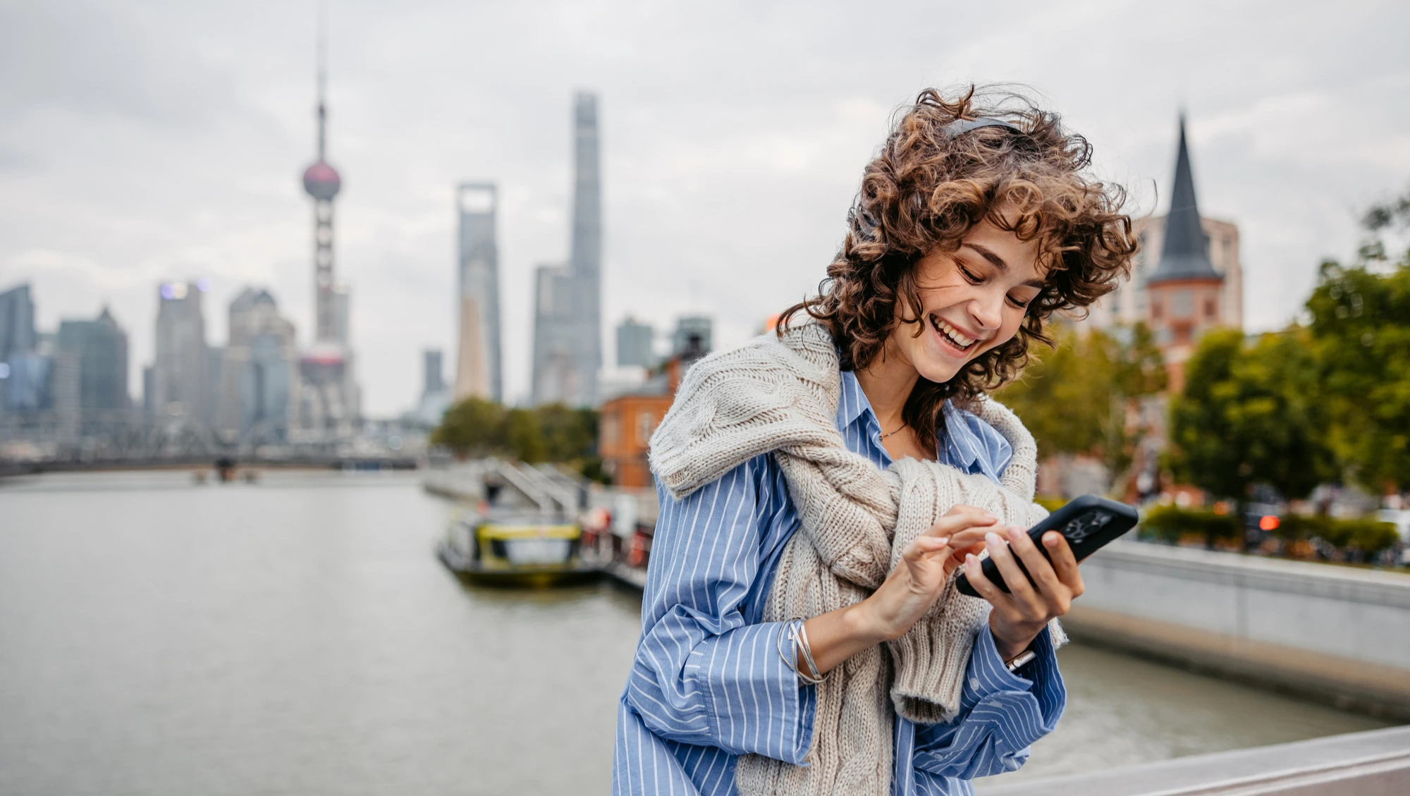 a young woman uses a travel app on her phone in a city