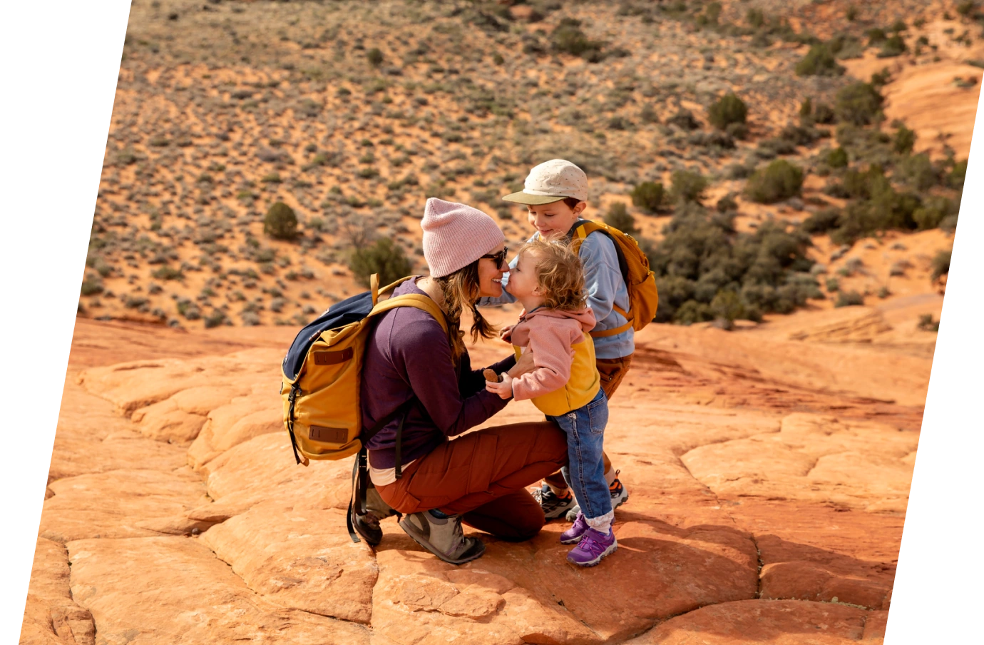 a mother with travel insurance with primary coverage crouches down next to her kids on a desert hike