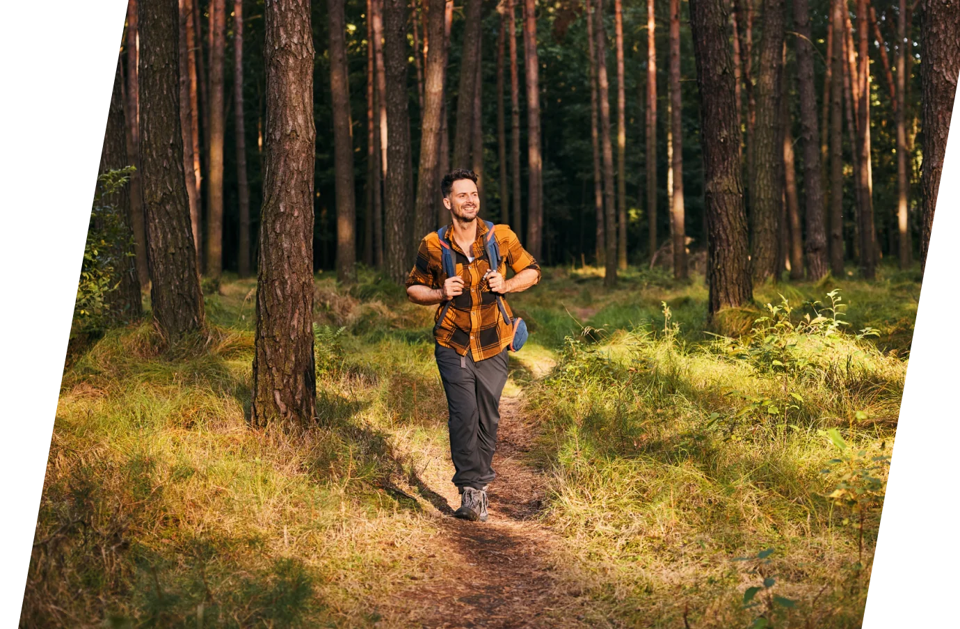 a young male with travel assistance hikes a forest trail wearing a backpack on a sunny day during his vacation