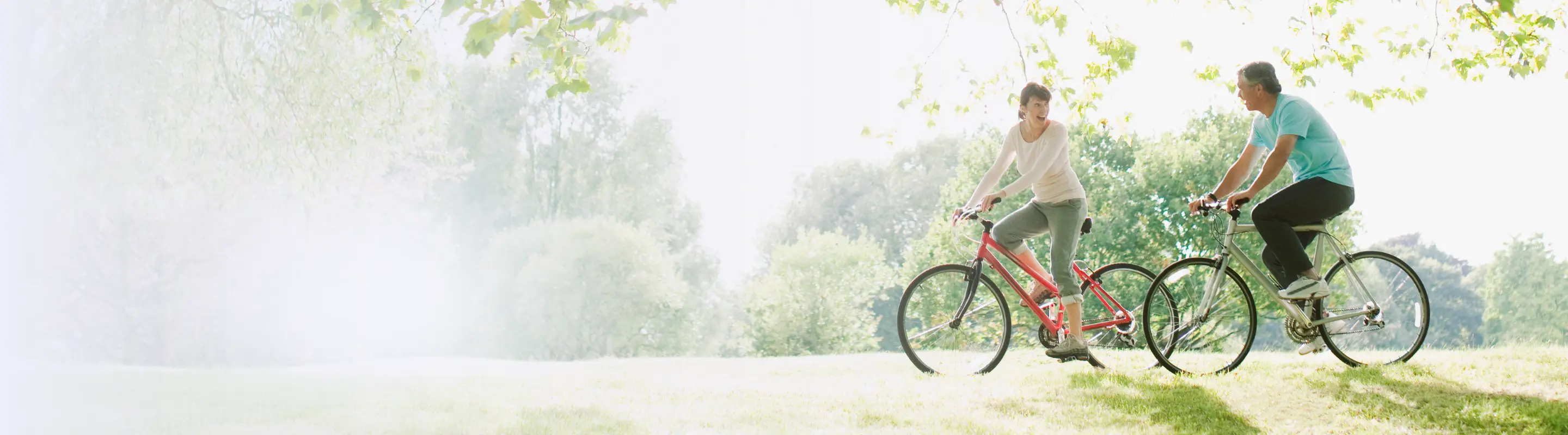a man and woman cycle through a green park on vacation after learning about Travelex insurance 
