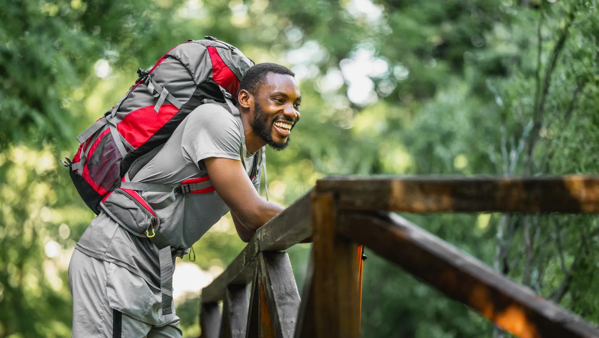 a backpacker rests on a forest bridge and smiles after reading our tips on how to be a responsible traveler 