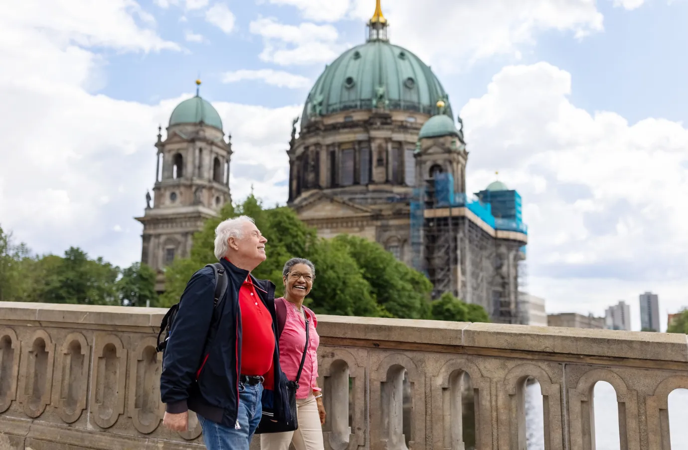 an older, mixed-race couple with pilgrimage travel insurance walks by an infamous cathedral in Berlin, Germany 