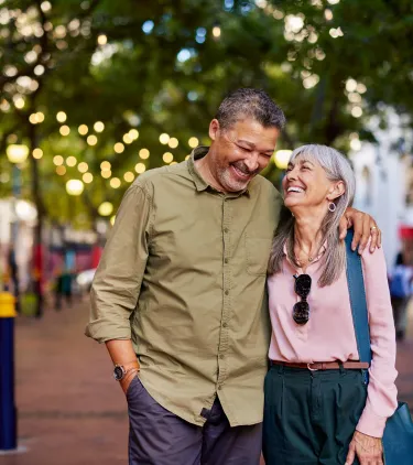 an older couple embraces as they walk through a quaint neighborhood, insured with travel insurance for city trips