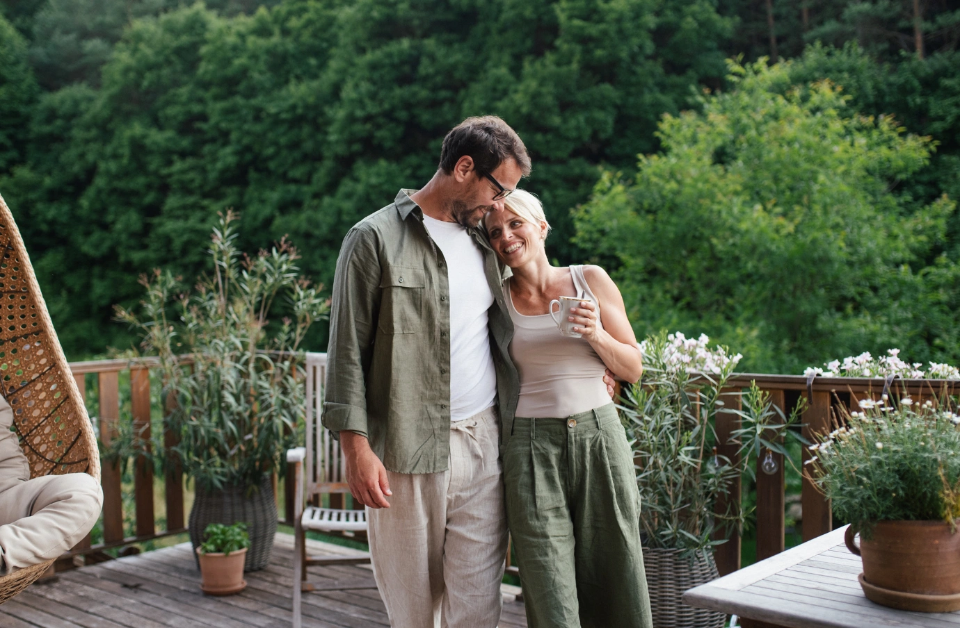 a couple with travel insurance for wellness retreats enjoys coffee on a wooden deck at a natural resort 