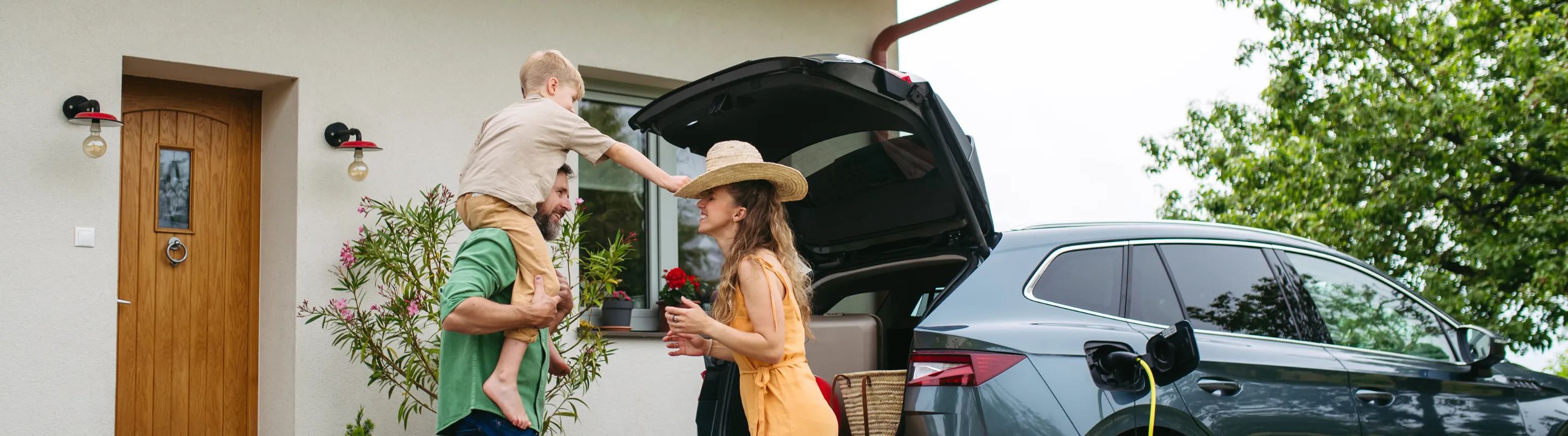 a family of three with road trip travel insurance arrives to their vacation rental and unloads their electric car